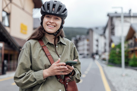 Woman cyclist portrait with gadget while stop on the bicycle path in cityの写真素材