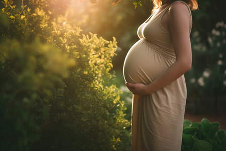 Pregnancy, motherhood. Happy pregnant woman with big belly in green gardenの素材