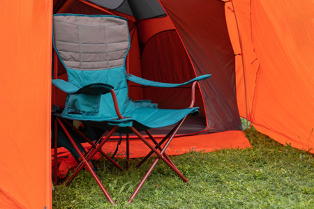 Camping chair stending near orange camp tent in the forestの写真素材