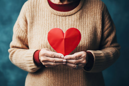 A female person holds in hands a paper heart with wishes, during celebrating St. Valentines Dayの素材
