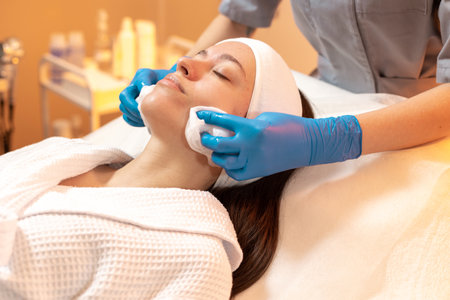 Woman receiving facial treatment in modern spa setting during daylight hoursの写真素材