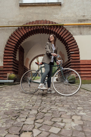 Stylish cyclist in tweed attire explores vintage architecture while riding a retro bicycleの写真素材