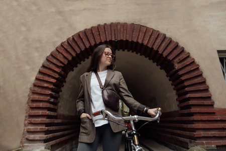 Riding a retro bicycle in tweed attire through an elegant brick archway in a local townの写真素材