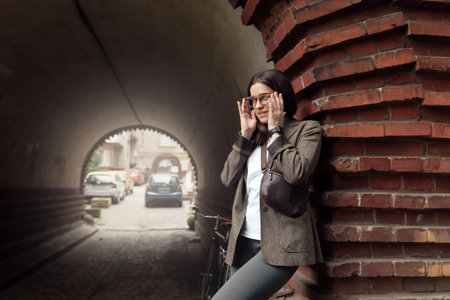 Cyclist in tweed outfit relaxing by a brick archway during a leisurely ride in a cityの写真素材