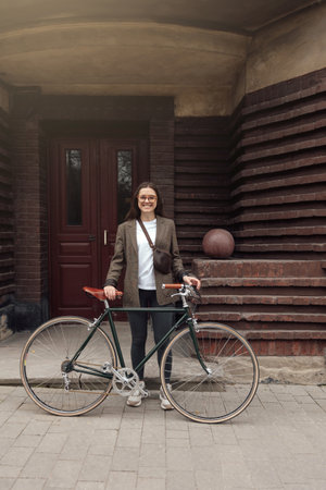 Rider in tweed attire poses with retro bicycle outside unique architectural buildingの写真素材