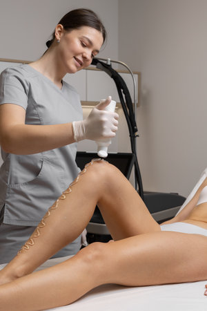 Woman receiving a beauty treatment at a modern clinic during a session focused on leg careの写真素材