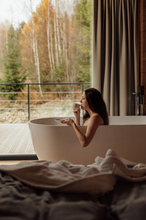 Enjoying a relaxing moment in a modern bathtub with a cup of teaの写真素材