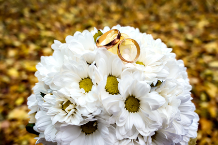 Gold rings on a bouquet of daisies.の写真素材