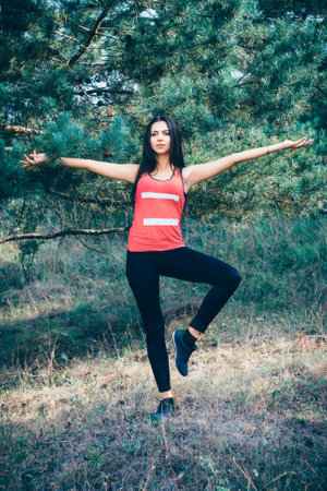 Young beautiful brunette tying shoes while jogging in the parkの写真素材