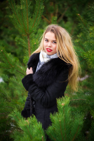 Young blond woman standing in pines and looking at camera.の写真素材