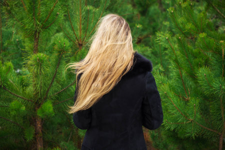 Young blond woman standing in pines winterの写真素材