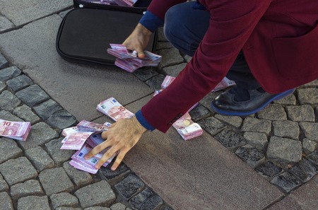 A businessman collects money from the ground.の写真素材