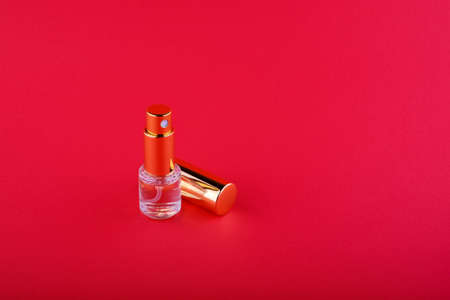bottle with liquid with a golden cap that lies next to it on a red backgroundの写真素材