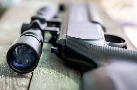 Sniper rifle lies on a wooden background. Optical sight close-up. The concept of hunting