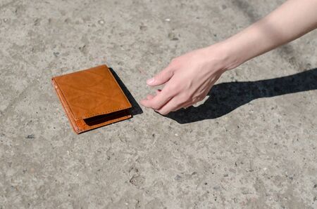 Girl picks up a brown wallet. Found a wallet on the road