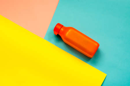 Orange plastic bottle for water close-up. Bottle on a three-color backgroundの写真素材