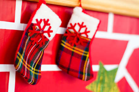 Christmas socks for gifts hang on the decorative fireplace. Greeting card.