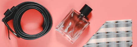 Banner mens perfume, tie and belt on a pink background. Male beauty concept. Panoramic photo of...