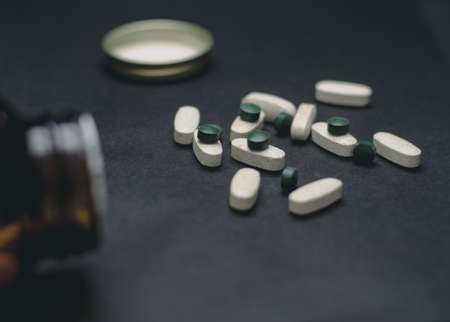 White and green pills on a black background