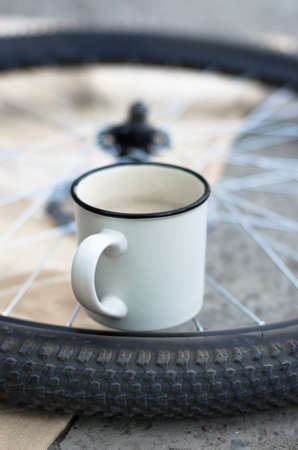 White cup with coffee on a bicycle wheel. Coffeetime.