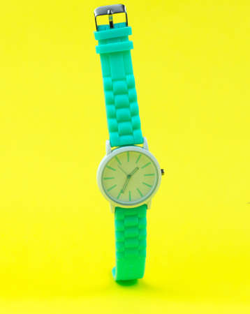 Stylish women's watch hangs in the air on a yellow background. Women's accessories.の写真素材