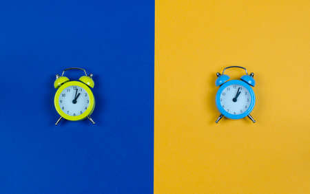 Clock on a yellow-blue background. Yellow clock on a blue background. Blue clock on yellow backgroundの写真素材