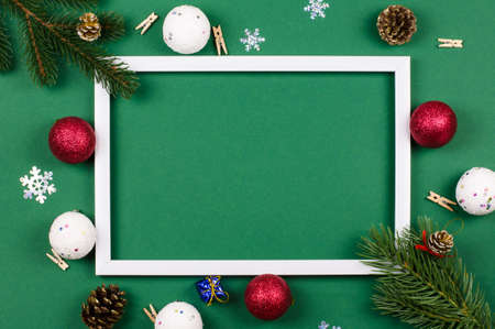 White frame with fir branches and New Year's toys on a green background. Christmas cardの写真素材