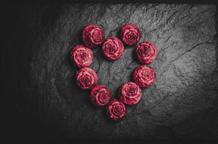 Red cupcakes in the form of a heart on a black background. Heart made from cupcakes.
