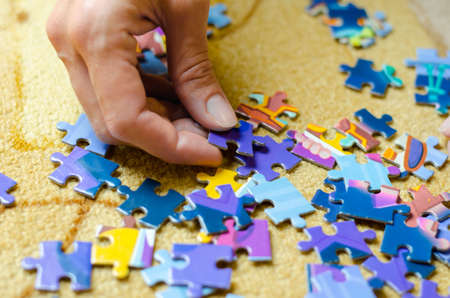 Women's hands collect the puzzle. Woman folds colorful mosaicの写真素材