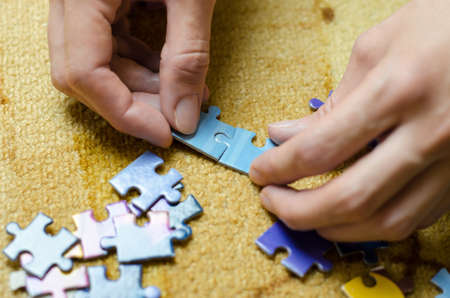 Women's hands collect the puzzle. Woman folds colorful mosaic