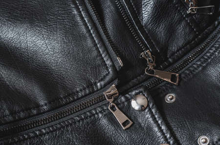 Metal zipper on a black women's jacket. Part of a leather jacket, top view. Black texture of genuine...