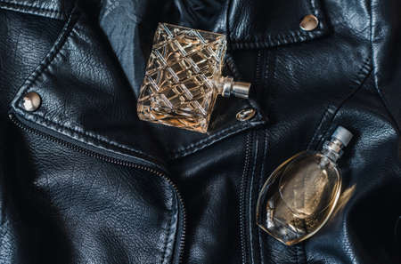 two bottles of women's perfume on a black leather jacketの写真素材