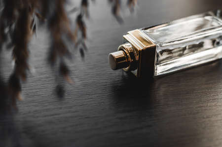 Golden bottle of women's perfume on a dark wooden backgroundの写真素材