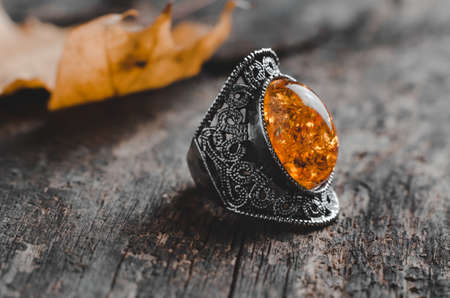 Vintage ring with large orange stone on old wooden background
