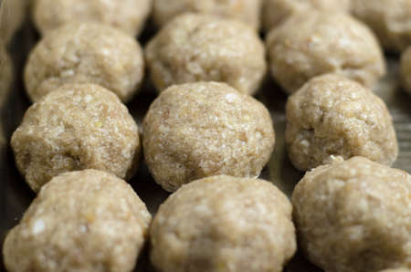 Close-up of raw meat patties on a baking sheet.