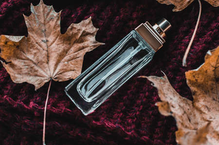 Perfume bottle on knitted texture with yellow leavesの写真素材