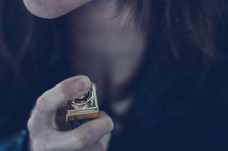 Perfume bottle in hand of young woman close up