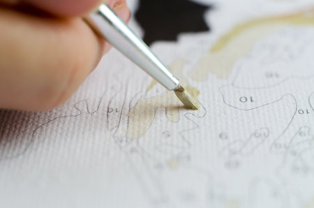 Woman paints on canvas. Woman's hand holding a brush for drawing close-upの写真素材