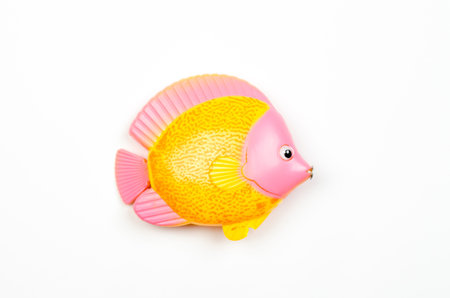 Toy plastic yellow-pink fish on white background