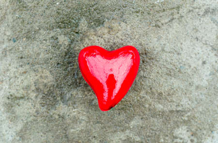 Big red heart in the snow on a concrete background
