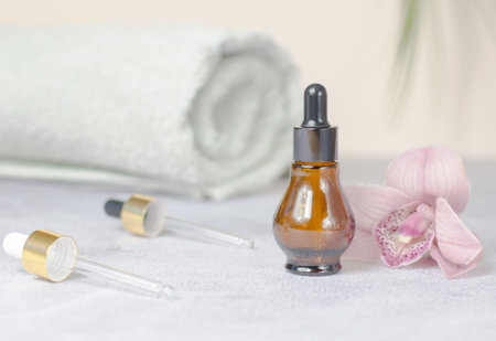 Beauty spa concept. Composition of natural stones, orchid flower, rolled white towel and bottle of essential oil.の写真素材