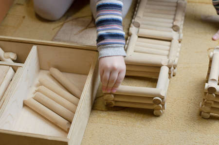 Child plays with wooden constructor in the room