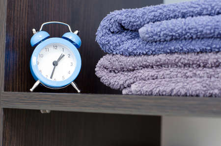Blue alarm clock on the shelf with bath towels. Massage timeの写真素材