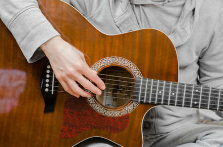 Woman musician plays the guitar. Fingers touch the strings close-upの写真素材