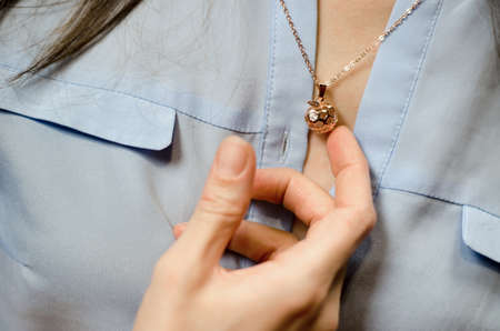 Gold-colored pendant on a woman's neck. Gilded apple-shaped decoration