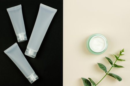White cosmetic tube for cream and an open jar of cream on a black and beige background, mock up....