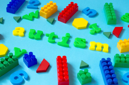 The word autism from colored letters on a blue background with elements of a child's constructorの写真素材
