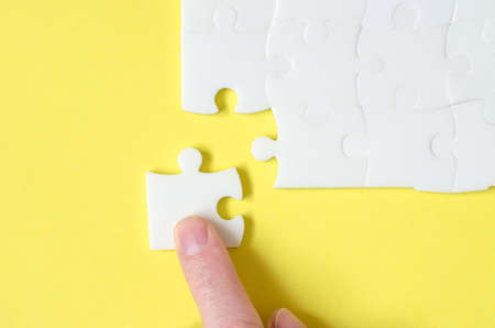 The hand lays down the missing piece of the puzzle. Last piece of jigsaw puzzleの写真素材