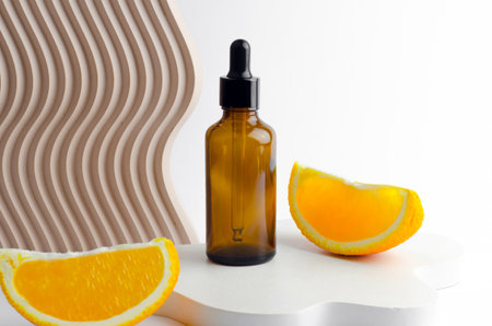 Serum in a glass bottle with a pipette. Natural essential oil on a white podium. Packaging for a cosmetic product. Oils with orange extractの写真素材