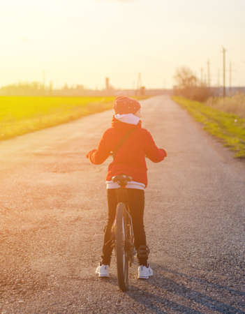 A girl on a bicycle stands on an empty road. Travel and healthy lifestyle conceptの写真素材